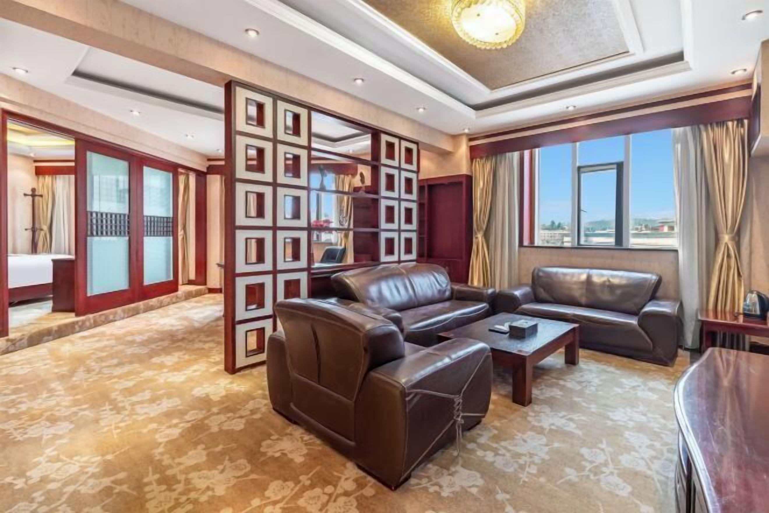 Un salón amplio con un sofá de cuero marrón, una mesa de centro y un separador de madera decorativo.