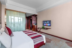 Una habitación de hotel con cama, televisión, escritorio y vistas al exterior.