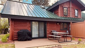 A log cabin with a covered patio, a barbecue grill, and a picnic table. - Cozy Log Cabin on Golf Course, Across from Otsego Lake (Gaylord)