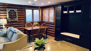 A cozy cabin-style room with a wooden dining table, chairs, and a potted plant. - Cozy Log Cabin on Golf Course, Across from Otsego Lake (Gaylord)