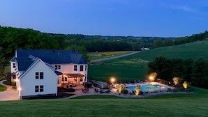 A large white house with a patio and pool area, surrounded by green fields and trees. - Liberty Hill Lodge, Hot Tub & Pool (New Philadelphia)