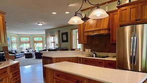A spacious kitchen with wooden cabinets, a stainless steel refrigerator, and pendant lighting. - Liberty Hill Lodge, Hot Tub & Pool (New Philadelphia)