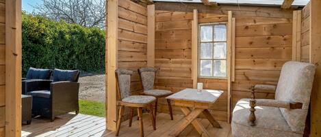 Une cabane en bois dotée d’un patio couvert comprenant une table et quatre chaises.