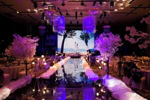 A stage with a backdrop, floral arrangements, and a reflective floor.