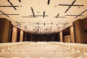 A large, empty auditorium with rows of white chairs and a stage at the front.