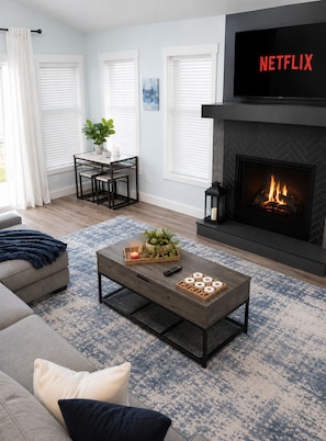 A living room with a sofa, coffee table, fireplace, and a TV displaying the Netflix logo. - Modern Poconos Cabin w/ Hot Tub Near Kalahari & CamelBack Mountain ! (Long Pond)