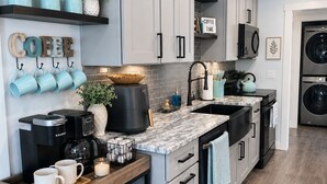 A modern kitchen with grey cabinets, a coffee station, a kettle, and a microwave. - Modern Poconos Cabin w/ Hot Tub Near Kalahari & CamelBack Mountain ! (Long Pond)