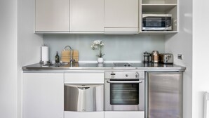 A modern kitchen with stainless steel appliances, including a dishwasher, oven, and microwave, and a built-in sink. - Light and convenient city living (Auckland)