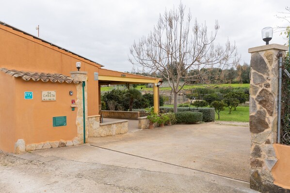 A building with a stone entrance, a covered area with steps, and a sign indicating a parking area.