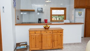 Een keuken met een houten aanrecht, een magnetron, een koffiezetapparaat en een koelkast.