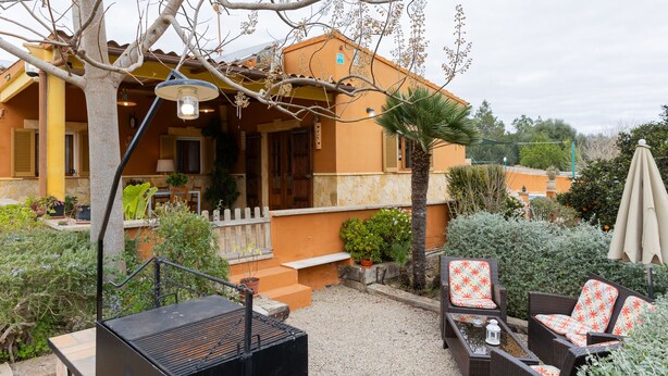 Een huis met een terras, tuinmeubilair en een barbecue.