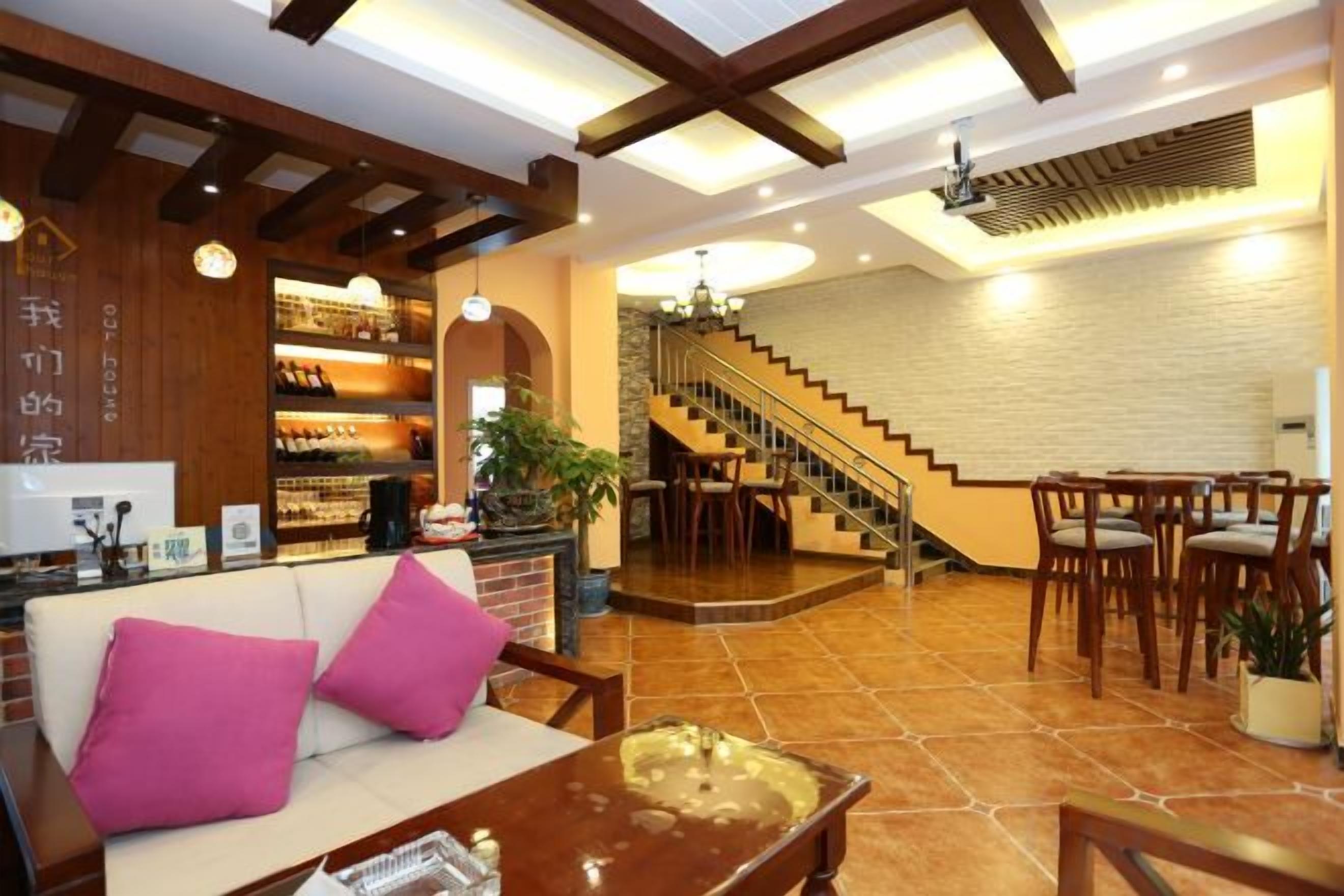 Un vestíbulo de hotel con mostrador de recepción, zona de estar, escalera y un bar.
