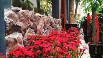 Un muro de piedra con flores rojas y plantas en macetas.