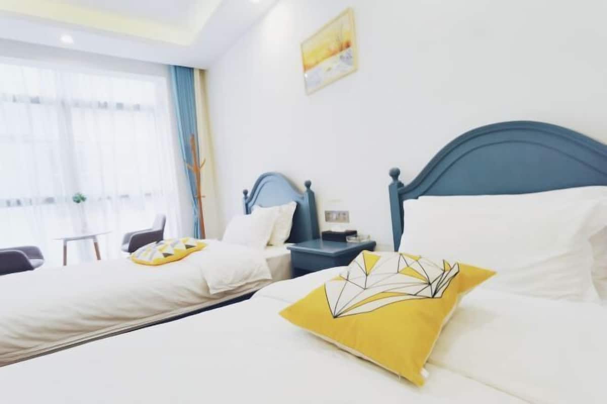 Een hotelkamer met twee bedden, een nachtkastje, een bureau en een raam met gordijnen.