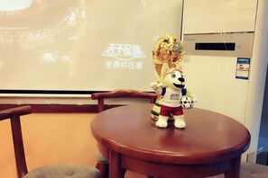 A plush toy on a round table with a projection screen in the background. - Jiuqi Our House (Zhangjiajie)