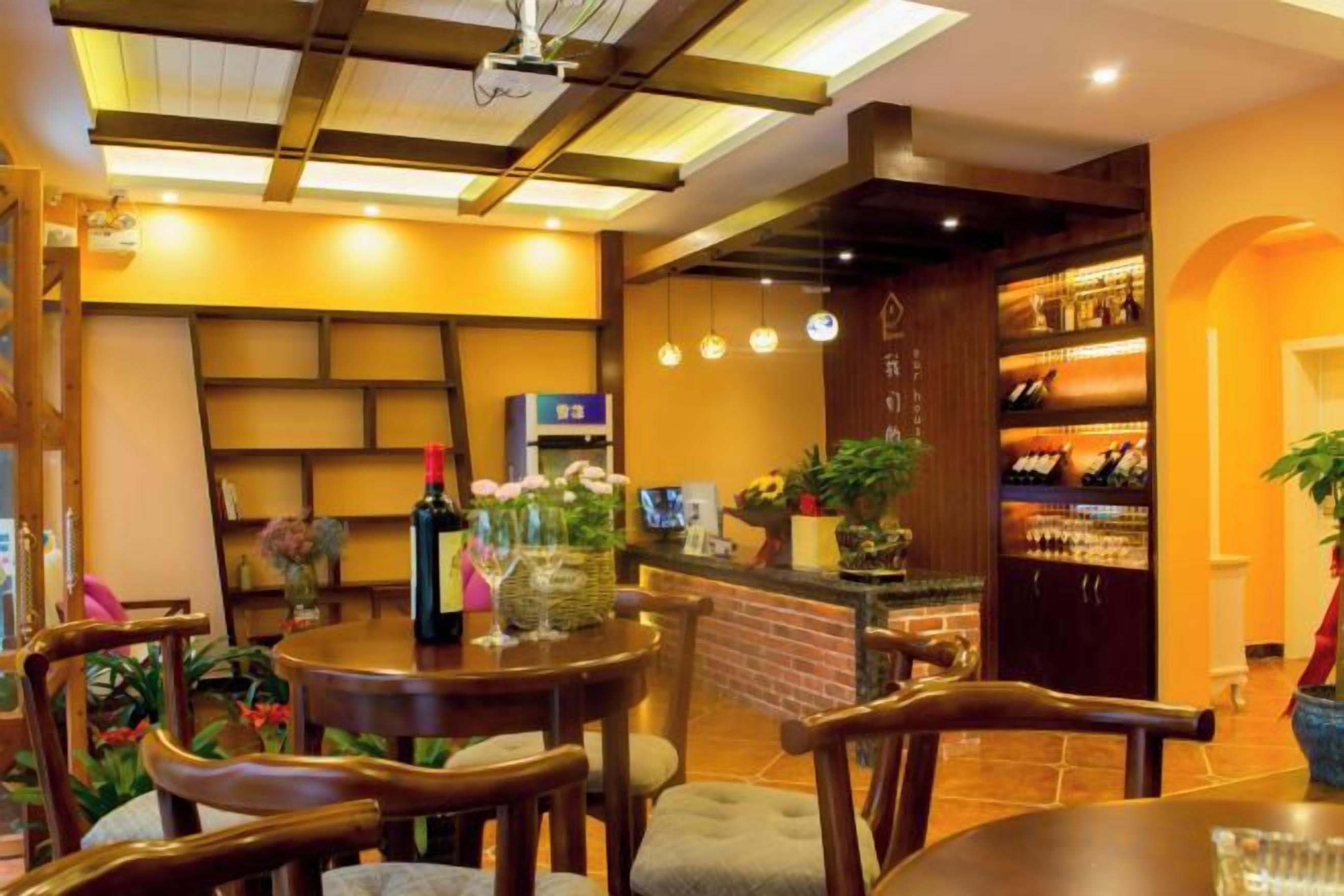 Interior de restaurante con mobiliario de madera, una zona de bar y estantes con botellas.