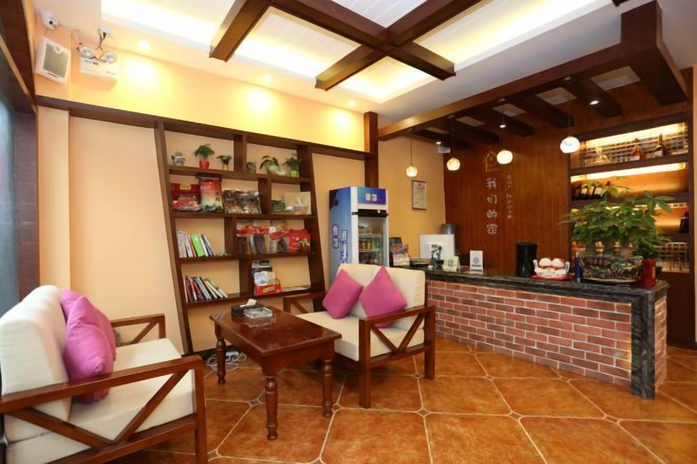 Un vestíbulo de hotel con asientos, una recepción, una estantería y una máquina de café.