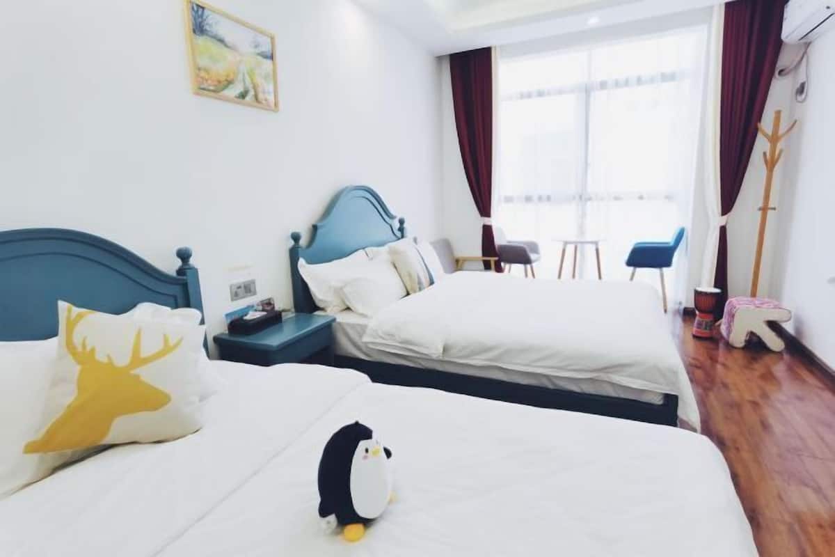 Een hotelkamer met twee bedden, een groot raam, een stoel en een klein tafeltje.