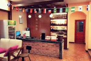 A bar area with a counter, seating, and a display of bottles. - Jiuqi Our House (Zhangjiajie)