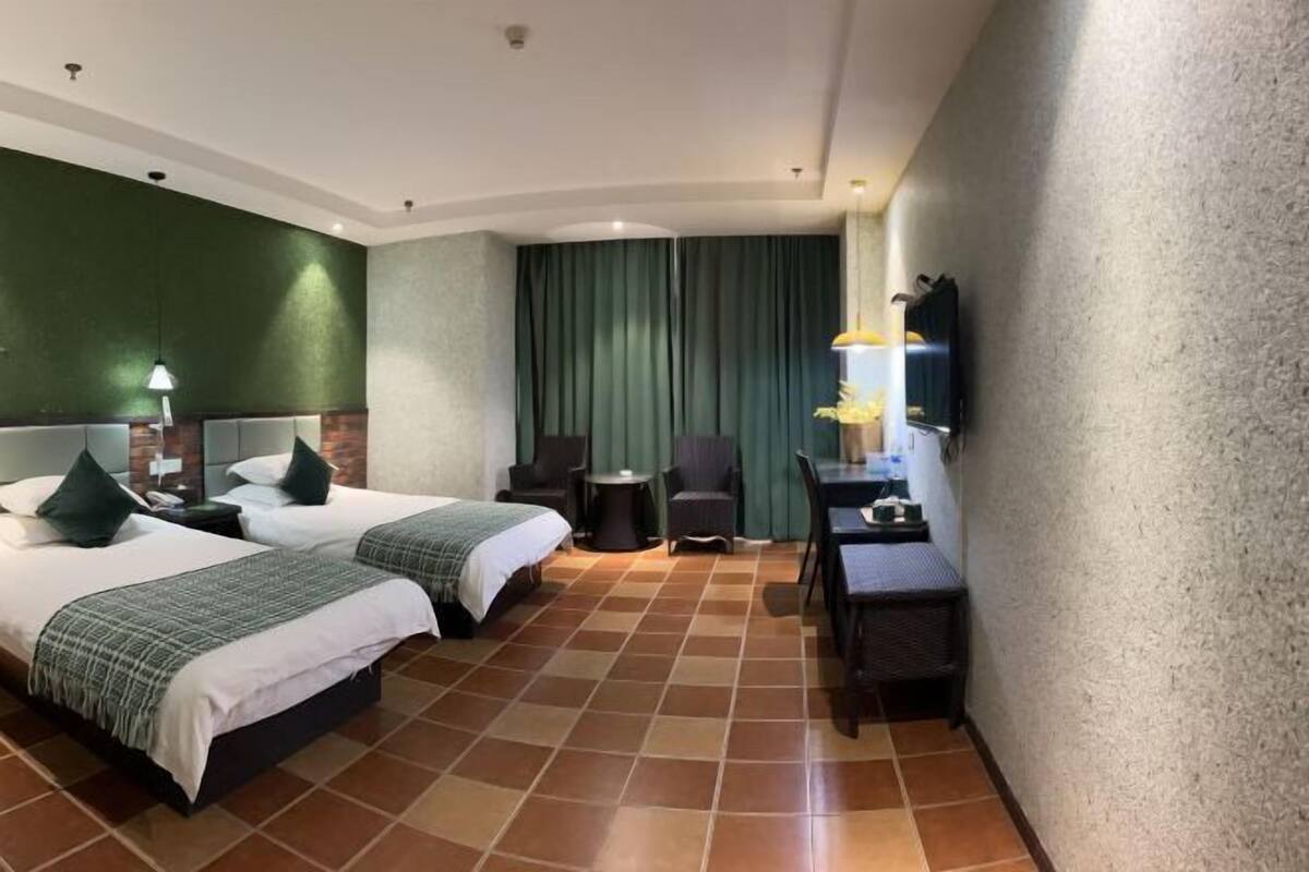 A hotel room with two beds, a small table, a chair, and a TV.