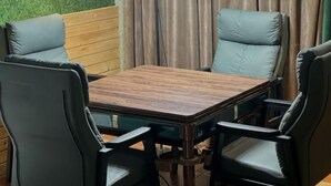 A dining area with a wooden table and four chairs, a green wall, and a curtain. - Fu'an Bojing Hotel (Fu'an)