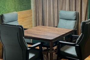 Un comedor con una mesa de madera y cuatro sillas, una pared verde y una cortina.