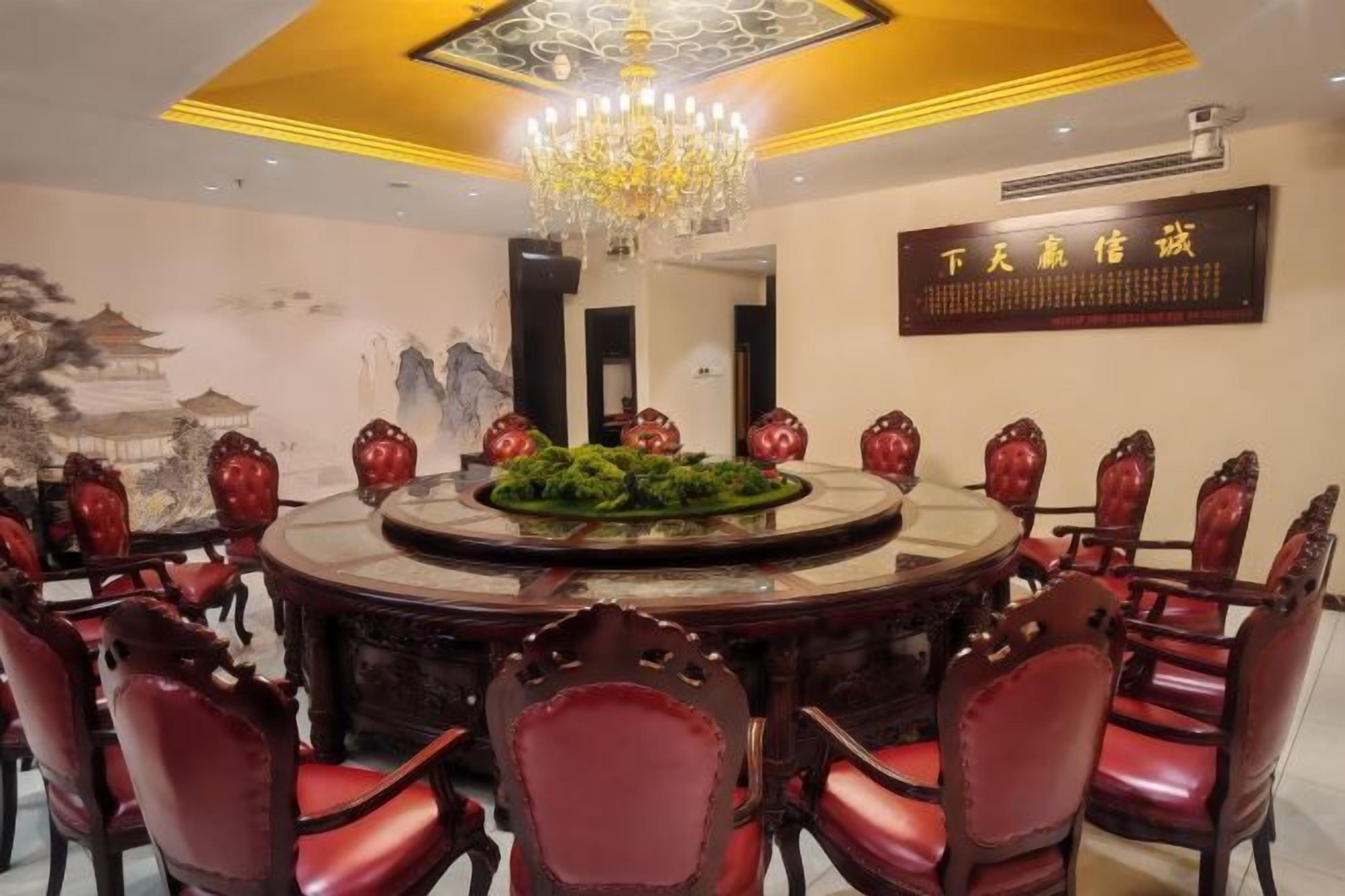 Ein runder Esstisch mit roten Stühlen, eine Chandelier und ein dekoratives Mittelstück.