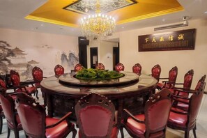 A round dining table with red chairs, a chandelier, and a decorative centerpiece.