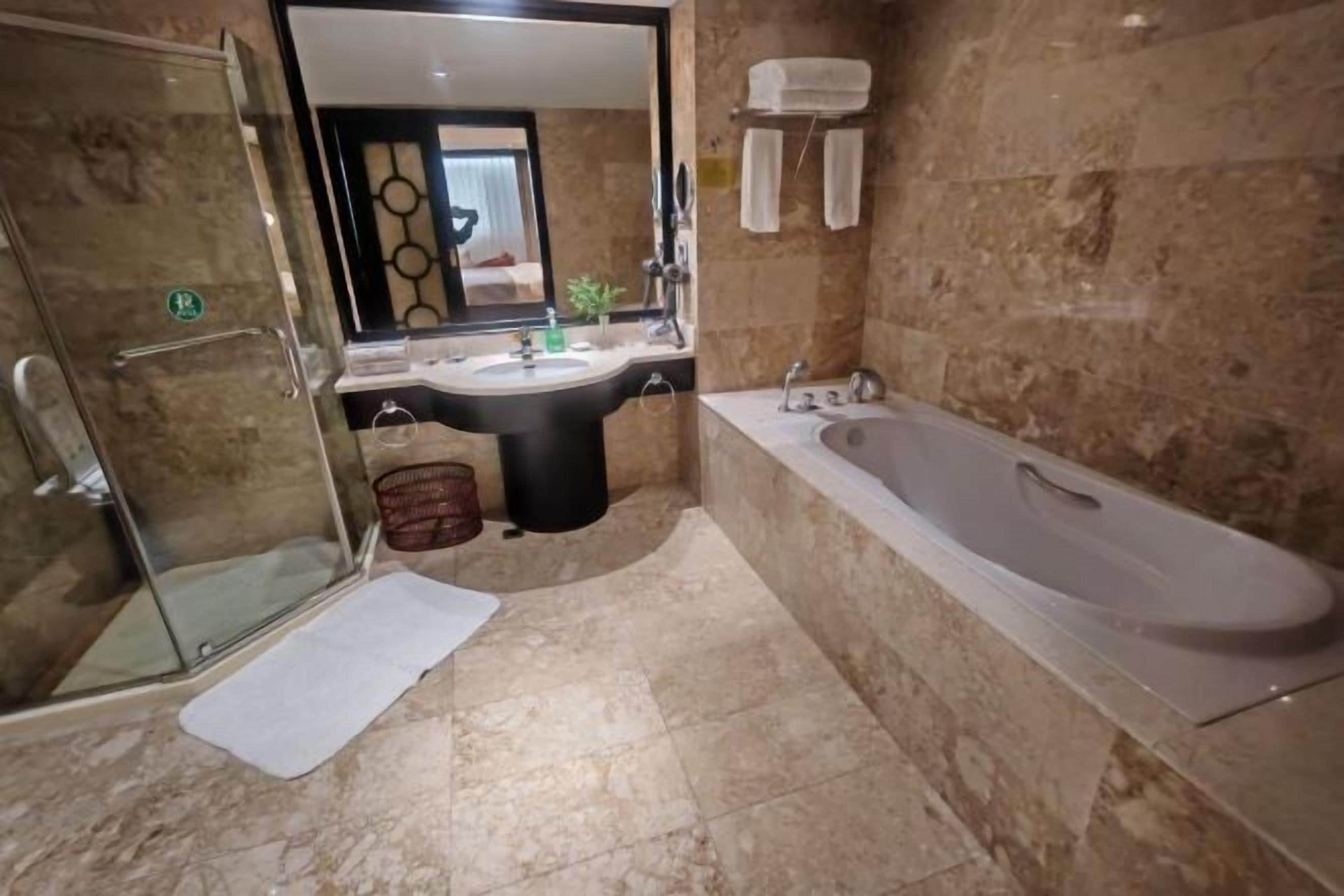 Un baño con cabina de ducha de vidrio, un lavabo, una bañera y un espejo.