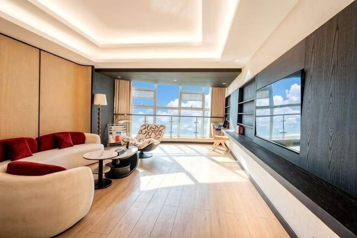 Una habitación de hotel moderna con sofá, sillón y una mesa de comedor.
