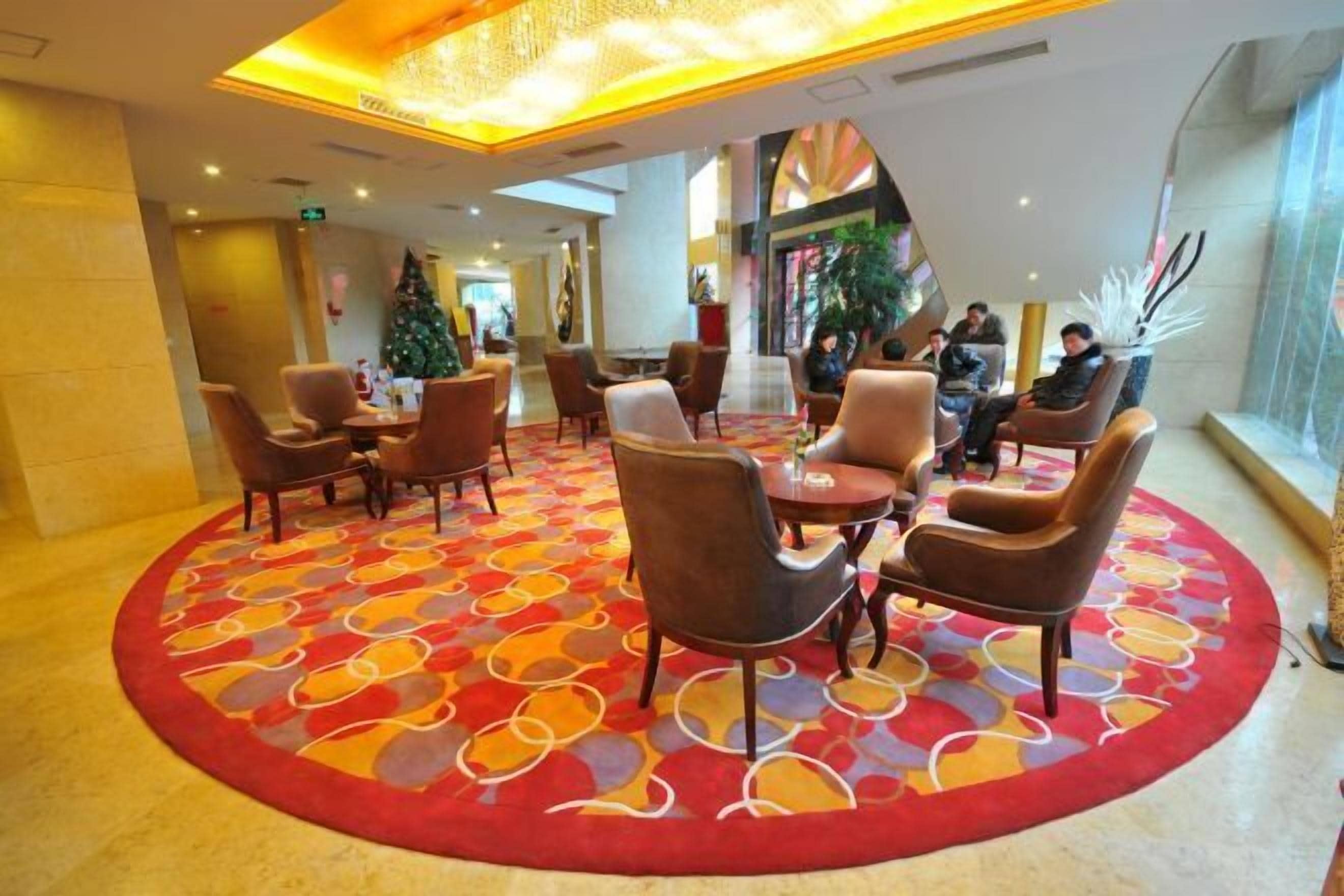 A lobby with a circular seating area, a Christmas tree, and a large window with a view.