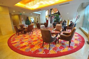 A lobby with a circular seating area, a Christmas tree, and a large window with a view.