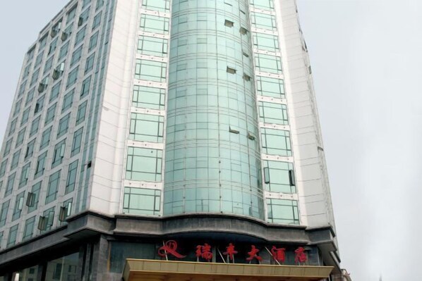 A tall building with a curved glass facade and a sign with Chinese characters.
