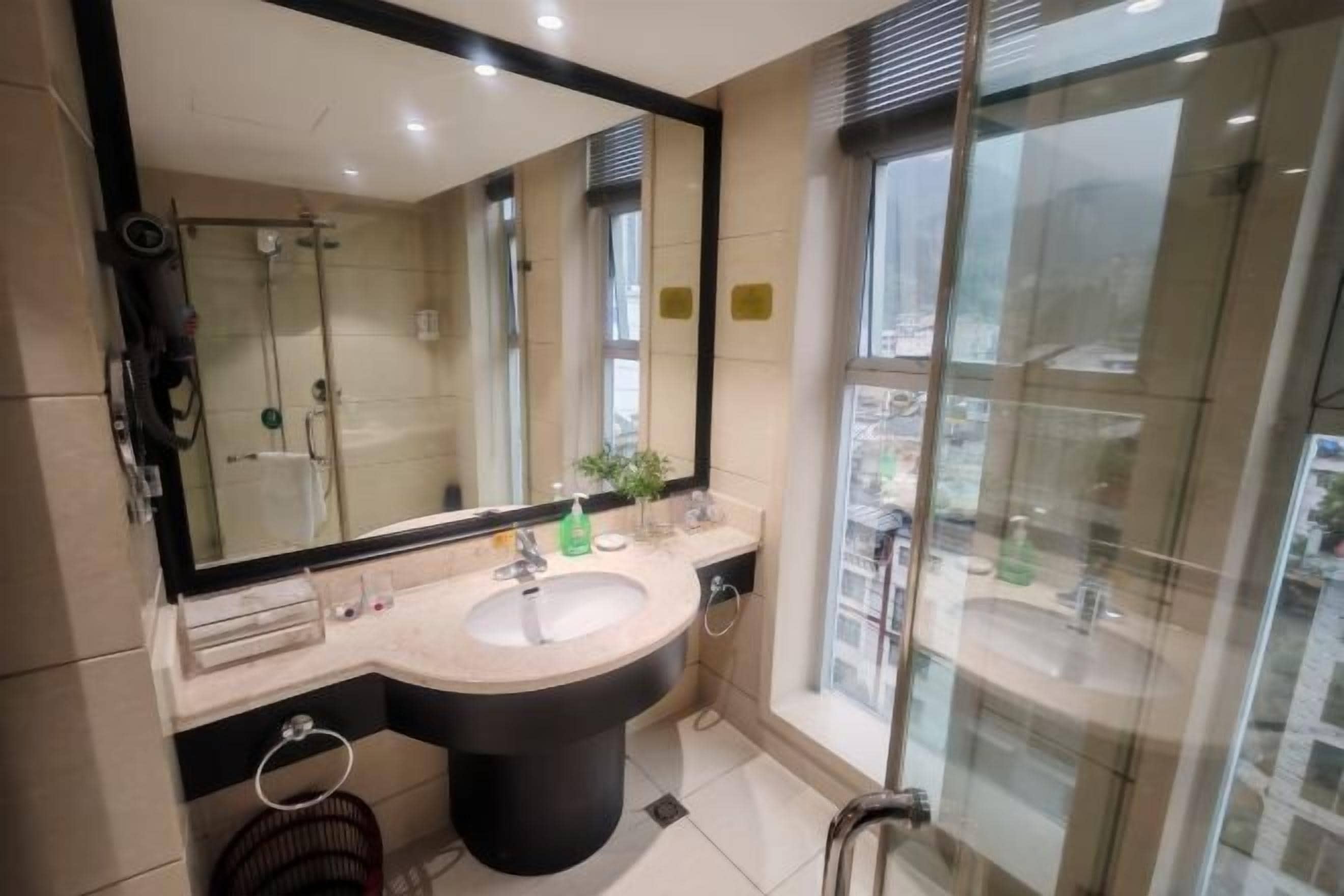 A modern bathroom with a large mirror, a sink, and a shower.