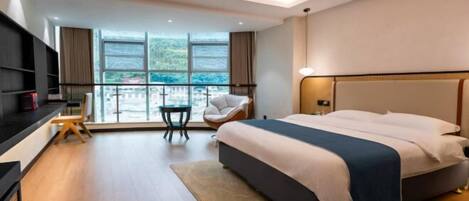 A modern hotel room with a large bed, a desk, and a view of the outdoors.