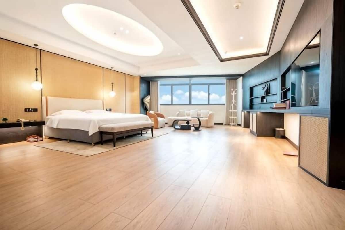 Una habitación de hotel moderna con una cama grande, un escritorio y un área de descanso.