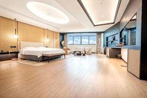 Una habitación de hotel moderna con una cama grande, un escritorio y un área de descanso.