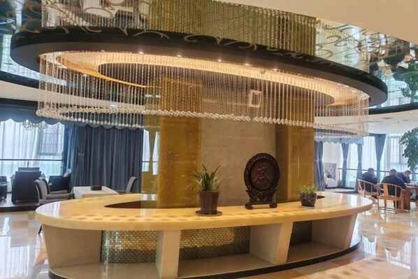 A lobby with a circular reception desk, a chandelier, and seating areas.