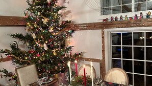Un comedor con un árbol de Navidad, velas y una mesa preparada para cuatro comensales.