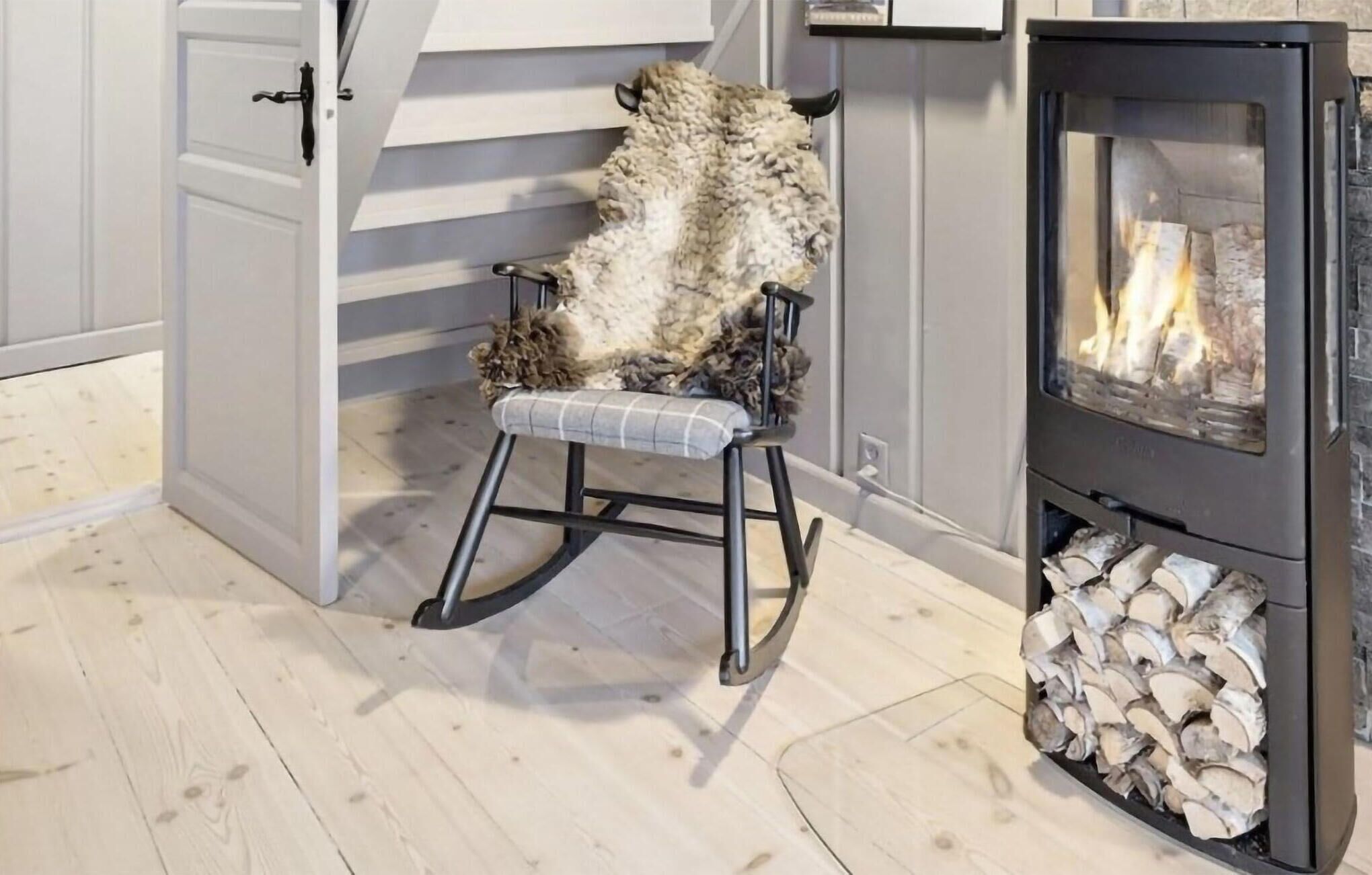 A room with a fireplace, a rocking chair, and a stack of firewood.