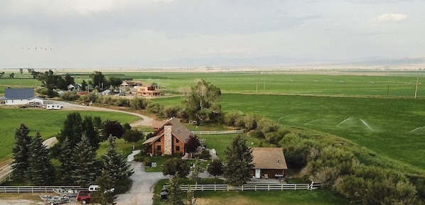Propiedad rural con una casa grande, una cabaña más pequeña y un potrero cercado.