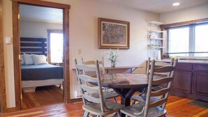 Una habitación con cama, una mesa de comedor con sillas, un cuadro en la pared y una ventana con vistas.