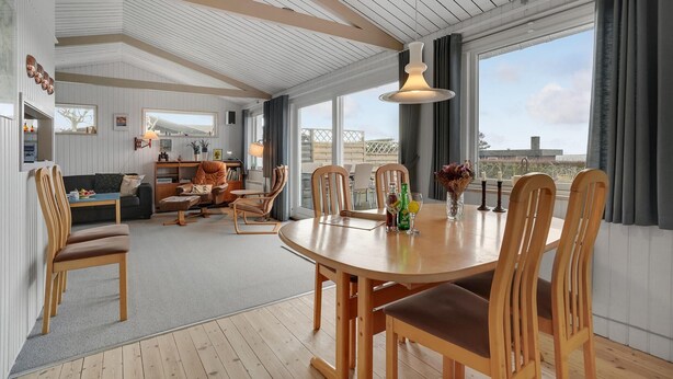 Un vaste espace de vie comprenant une table à manger, des chaises et un canapé. Une grande fenêtre offre une vue sur l’extérieur.