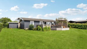 Une maison de plain-pied dotée d’un patio couvert, d’un garage et d’une pelouse bien entretenue.