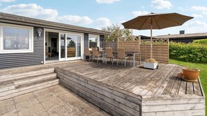 Une terrasse en bois avec des meubles d’extérieur et un grand parasol.
