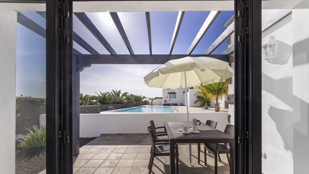 Eine Terrasse mit Pool, Sitzgelegenheiten im Freien und einer Pergola.