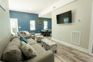 A living room with a sofa set, a dining table, and a TV mounted on the wall. - Lake living at its best! (Cedar Bluff)
