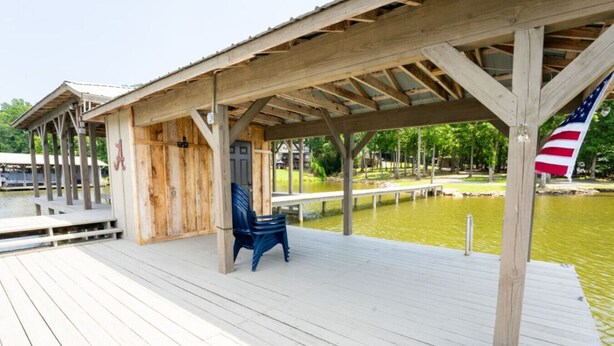 Une terrasse en bois dotée d’un espace abrité, d’un banc et d’un drapeau américain.