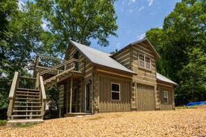 A rustic wooden cabin with a staircase leading to a porch, surrounded by trees and gravel. - Lake living at its best! (Cedar Bluff)