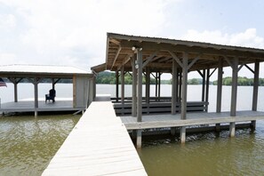 A wooden pier leading to a covered dock with a bench and an American flag. - Lake living at its best! (Cedar Bluff)